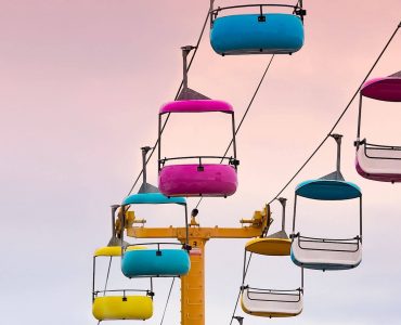 a group of colorful chairs sitting on top of a wooden pole