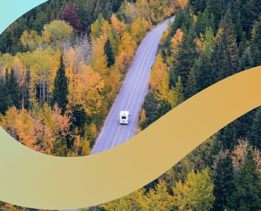 a truck driving down a road surrounded by trees
