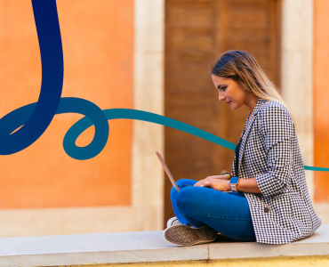 a woman sitting on a ledge using a laptop computer