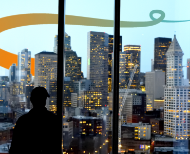 a man standing in front of a window looking out at a city