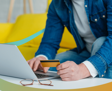 a man sitting at a table with a laptop and a credit card