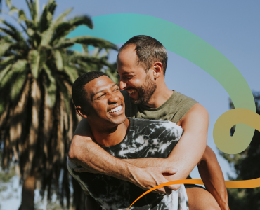 a couple of men hugging each other in front of a palm tree