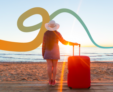 a woman standing on a beach next to a red suitcase