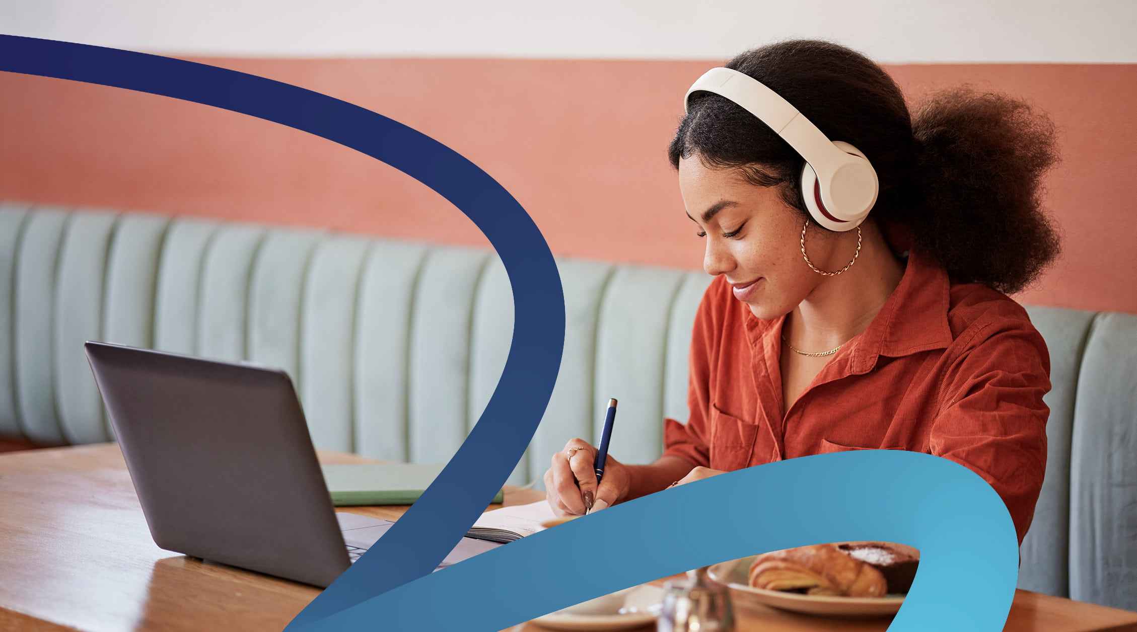 a woman sitting at a table with a laptop and headphones on