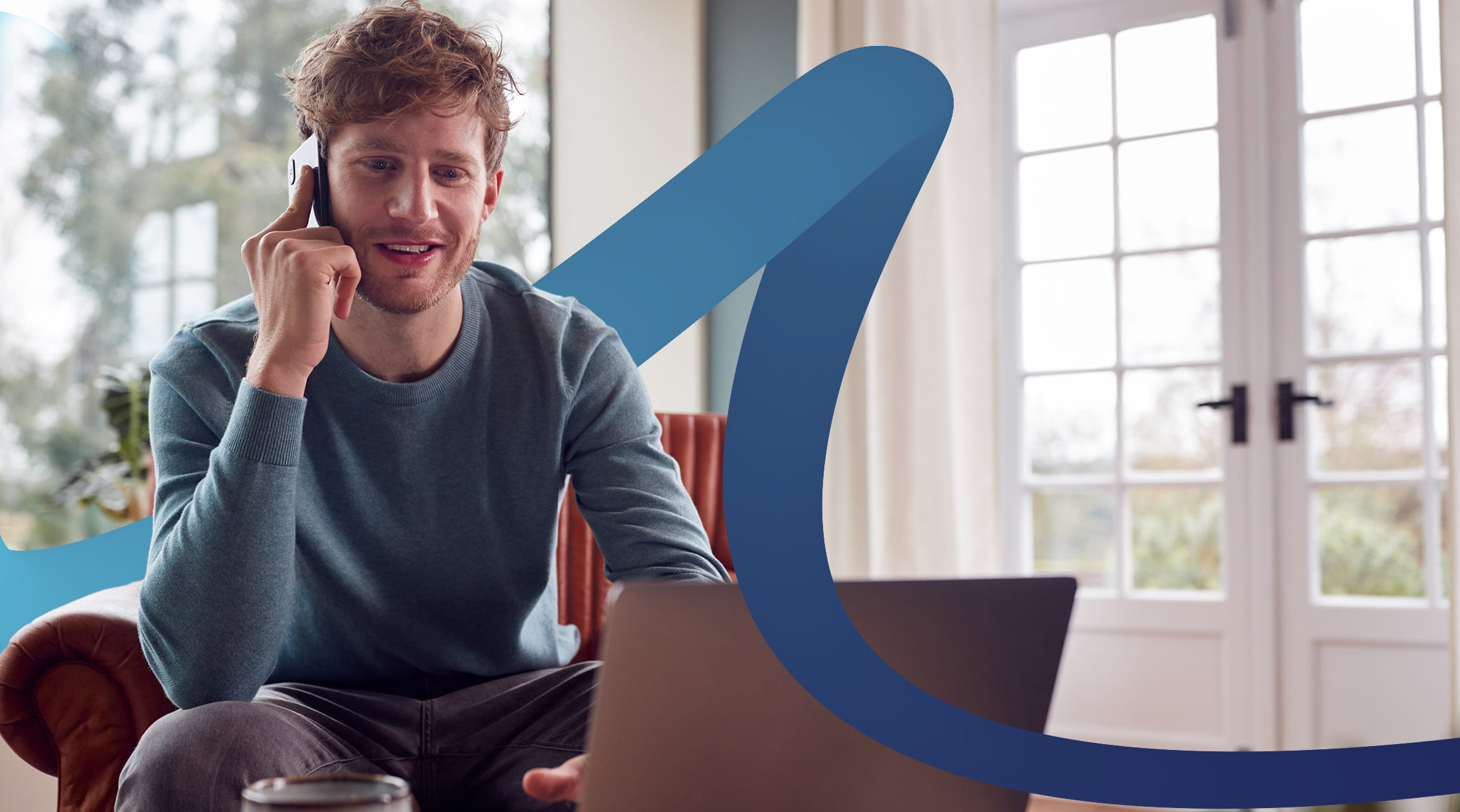 a man talking on a cell phone while sitting in front of a laptop